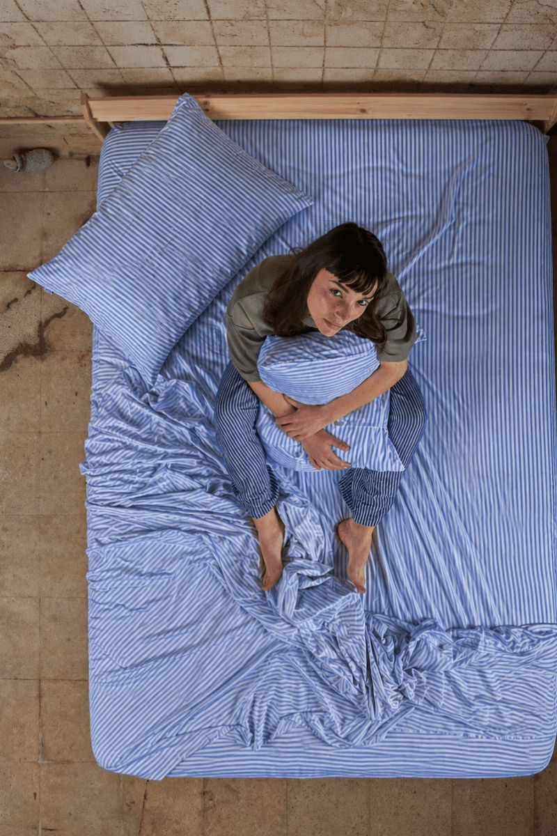 Frau liegt auf dem Bett mit blauem gestreiftem Bamboo-Baumwoll-Bettwäscheset von oben