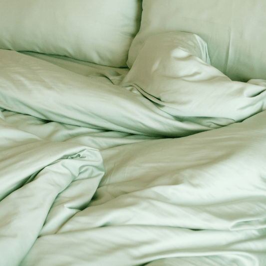 Jogo de cama em bambu verde sálvia exibido na cama mostrando lençol ajustável, lençol de cima, fronha e capa de edredão