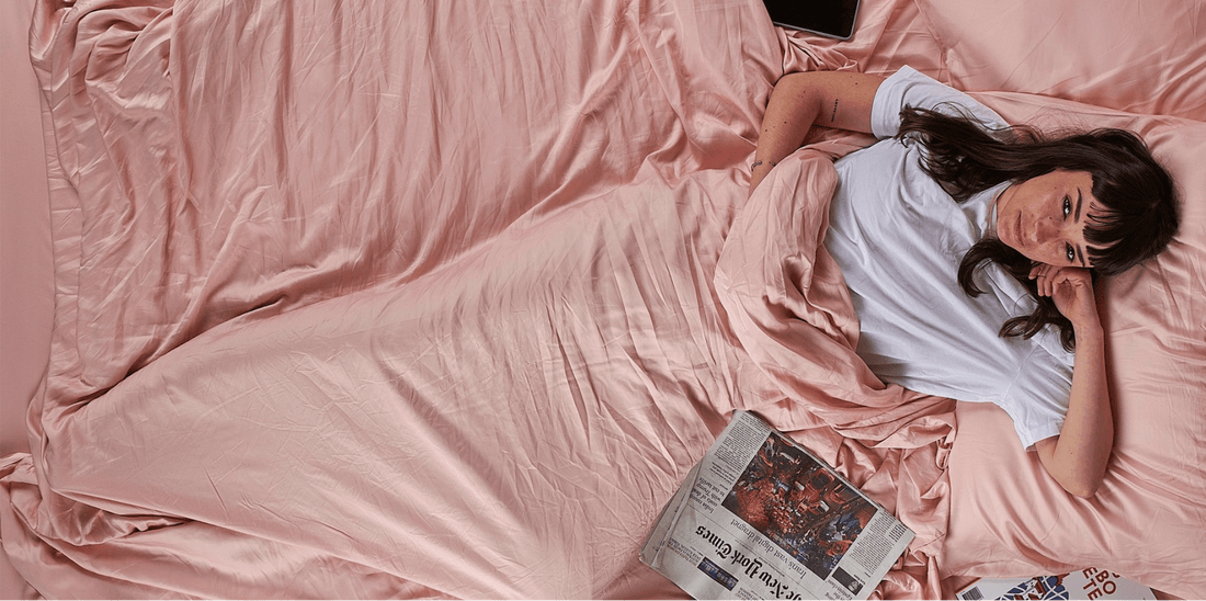 Frau liegt auf einem Bett mit rosa Bettwäsche und liest eine Zeitung, Frühjahrsschlafzimmerdekoration.
