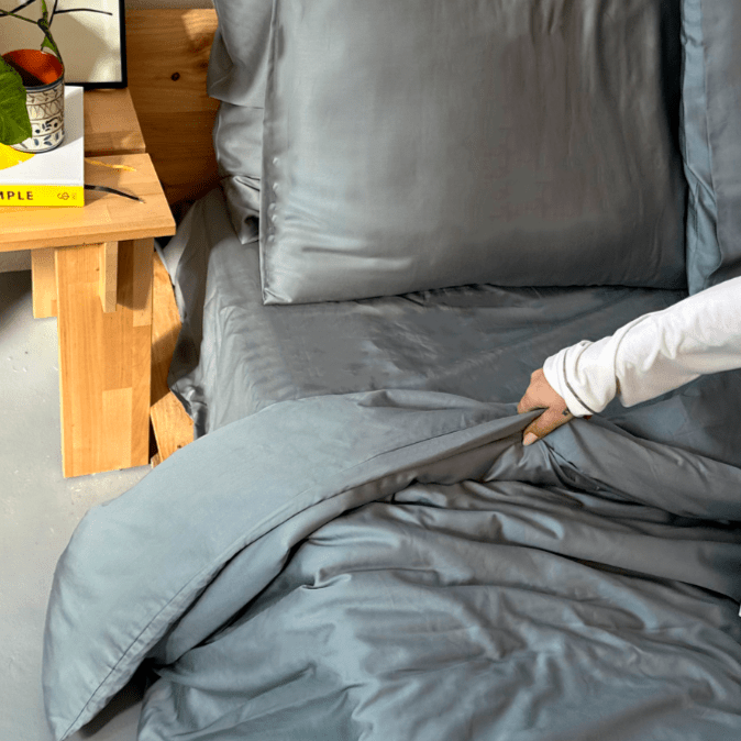 Frau berührt graue Bambussets auf dem Bett mit Holztisch im Hintergrund