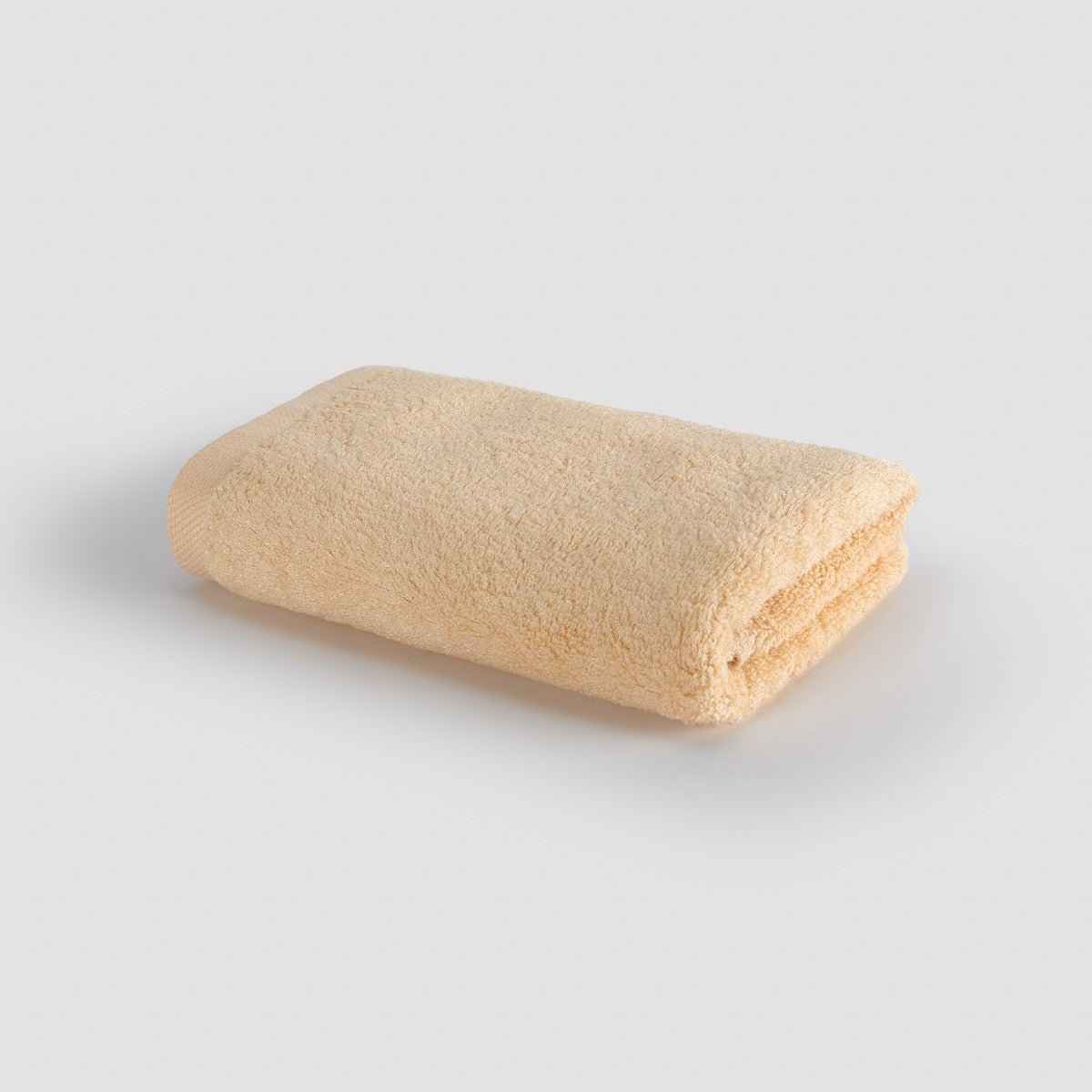 Beige folded towel on white background, top view