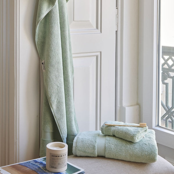 Mintgrünes Bambus-Handtuch-Set von Alba auf der Fensterbank mit gerollten Handtüchern und Zahnbürste