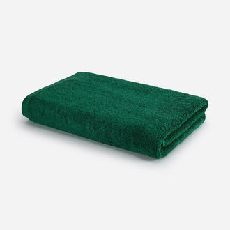 Waldgrünes Badetuch gefaltet auf weißem Hintergrund, Wabi-sabi Design von Momo Cotton