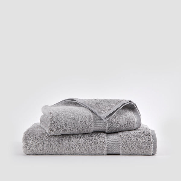Grauer Bambus-Handtuchsatz gestapelt auf weißem Hintergrund mit Gesichts-, Hand- und Badetüchern