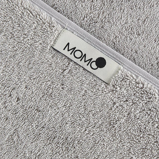 Graues Bambus-Handtuch mit momo-cotton Markenetikett auf weißem Saum, Nahaufnahme der weichen Textur