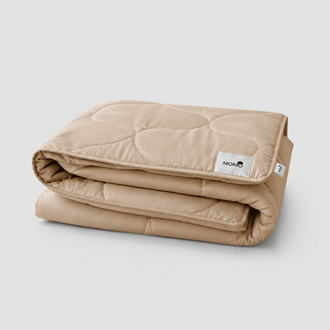 Beige gesteppte Sommerdecke gefaltet mit sichtbarem Momo-Tag auf weißem Hintergrund