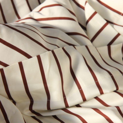 Cream bamboo sateen top sheet with burgundy stripes, folded to showcase striped pattern and finish