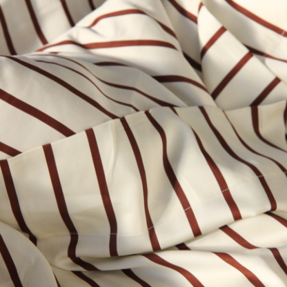 Cream bamboo sateen top sheet with burgundy stripes, folded to showcase striped pattern and finish