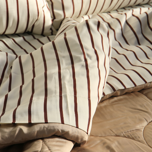 Silky bamboo top sheet with brown stripe pattern on bed with beige pillow