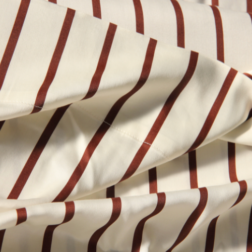 Red and white striped adjustable bamboo fitted sheet, folded showing silky fabric texture