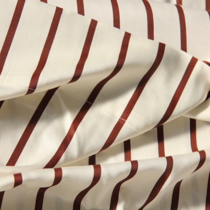 Red and white striped adjustable bamboo fitted sheet, folded showing silky fabric texture