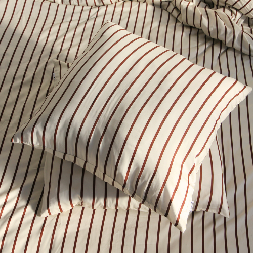 Par de fronhas de bambu acetinado com padrão de riscas, sobre cama