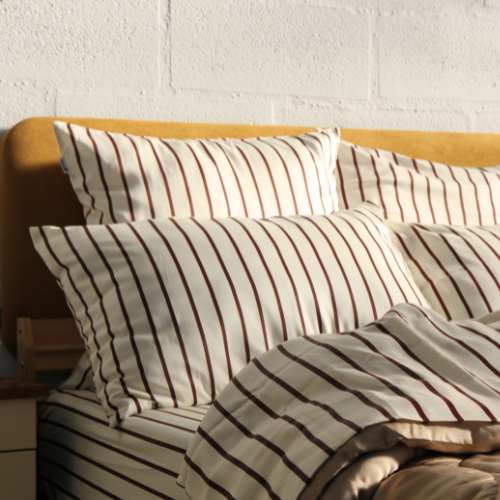 Bamboo striped sheet set with matching pillows on light wood bed frame
