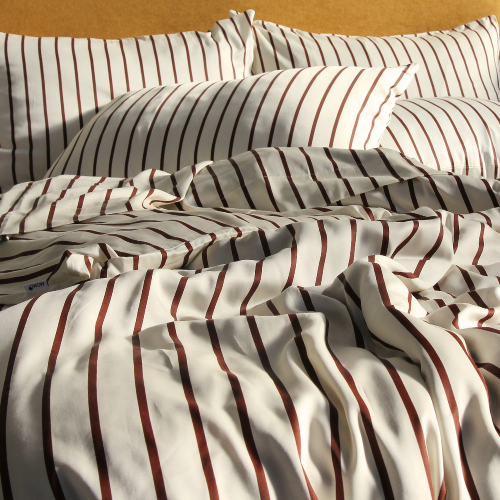 Complete bamboo bedding set with red striped pattern, featuring neatly folded pillowcases and sheets on bed