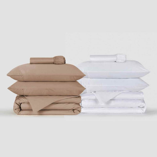 Beige- und weiße Bettdeckenbezug-Sets gestapelt mit gefalteter Bettwäsche, Kissen und Laken von Momo Cotton