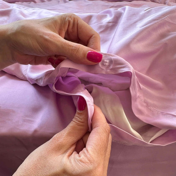 Nahaufnahme von rosa Bambus-Bettdeckenbezugsknöpfen beim Schließen – hochwertig, weich und nachhaltig